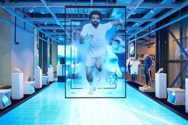 Modern exhibit featuring multiple transparent screens with images of footballer Mohamed Salah. A digitally enhanced floor with dynamic light effects, including DMX controlled LED Light Sheets, leads to a large screen at the back, creating an immersive, high-tech sports environment.